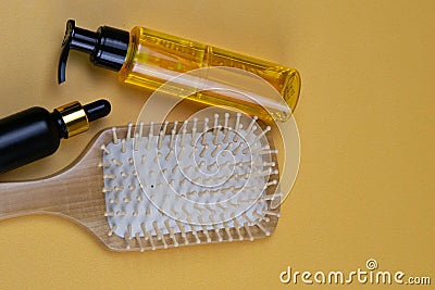 Cosmetics for hair care with jojoba, argan or coconut oil. Oil bottles and combs on orange background Stock Photo