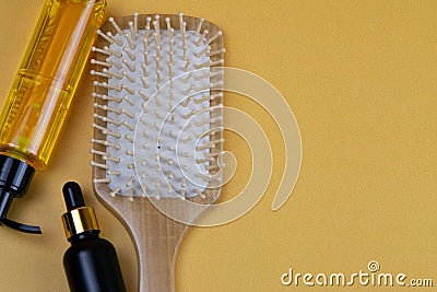 Cosmetics for hair care with jojoba, argan or coconut oil. Oil bottles and combs on orange background Stock Photo