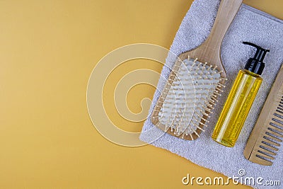 Cosmetics for hair care with jojoba, argan or coconut oil. Oil bottles and combs on a towel that stands on an orange background Stock Photo