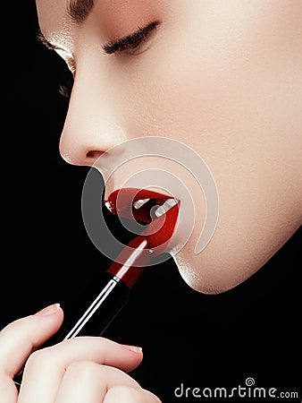 Cosmetics and makeup. Perfect lip makeup. Fashion model applying lipstick. Beautiful young woman Stock Photo