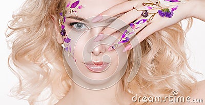 Cosmetics and manicure. Close-up portrait of attractive woman with dry flowers on her face, pastel color of nail design Stock Photo