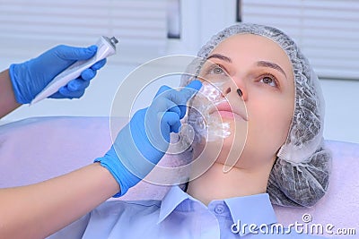 Cosmetologist is applying cream with anesthesia on patient`s face, closeup view. Stock Photo