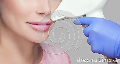 The cosmetologist does the procedure for laser hair removal of unwanted hair of the face to a young girl in a beauty salon Stock Photo