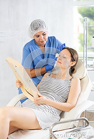 Cosmetologist examine patients contour face after lifting oval of face and palpate cheekbones Stock Photo