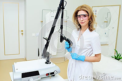 cosmetologist with glasses holds a CO2 fractional ablative laser for skin rejuvenation and scar removal in his hands and Stock Photo
