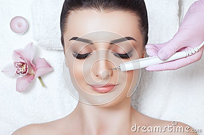 The cosmetologist makes the apparatus a procedure of Microcurrent therapy of a beautiful, young woman in a beauty salon Stock Photo