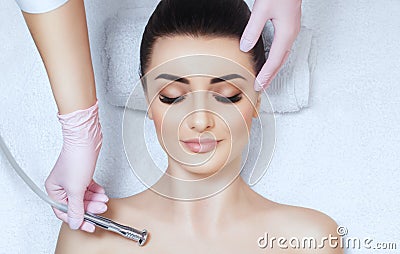 The cosmetologist makes the procedure Microdermabrasion on the collarbone and neck of a beautiful, young woman in a beauty salon Stock Photo