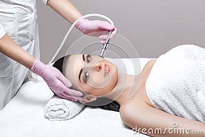 The cosmetologist makes the procedure Microdermabrasion of the facial skin of a beautiful, young woman in a beauty salon Stock Photo