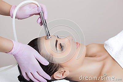 The cosmetologist makes the procedure Microdermabrasion of the facial skin of a beautiful, young woman in a beauty salon Stock Photo