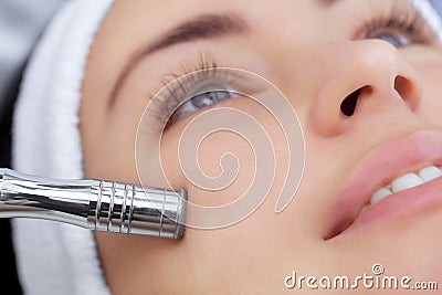 The cosmetologist makes the procedure Microdermabrasion of the facial skin of a beautiful, young woman Stock Photo