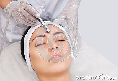 The cosmetologist makes the procedure Microdermabrasion of the facial skin of a beautiful, young woman Stock Photo