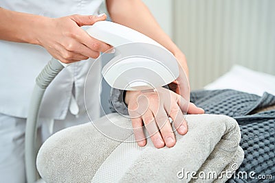 Cosmetologist performs a photorejuvenation procedure on the patiens hands Stock Photo