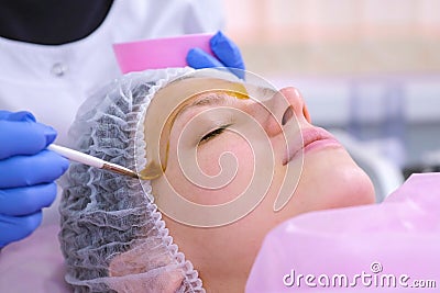 Cosmetologist puts chemical peeling of the woman`s face with brush. Cleaning the face skin and lightening freckles skin. Stock Photo