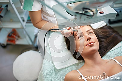 Cosmetologist is undergoing microdermabrasion of skin on female Stock Photo