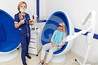 Cosmetologist whitens the patient`s teeth Stock Photo