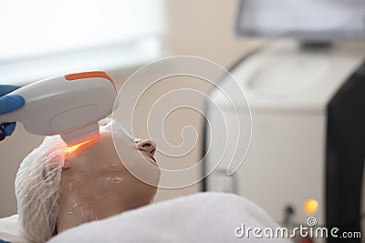 Cosmetology Concepts. Beautician Using Laser Therapy For Facial Skin Rejuvenation for Body Treatment of Healthy Woman Face Getting Stock Photo