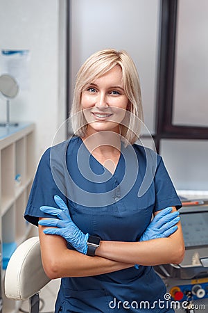 Cosmetology Service. Young doctor in gloves at beauty clinic standing crossed arms smiling confident Stock Photo