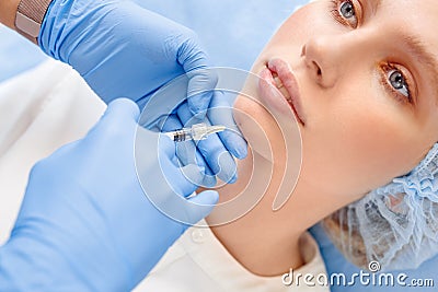 Cosmetology Service. Young woman at beauty clinic lying while doctor in gloves doing injection of hyaluronic acid into Stock Photo