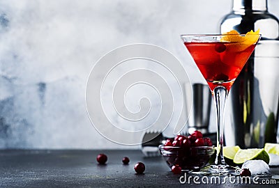 Cosmopolitan cocktail with vodka, liqueur, cranberry juice, lime, ice and orange zest, gray bar counter background, bartender Stock Photo