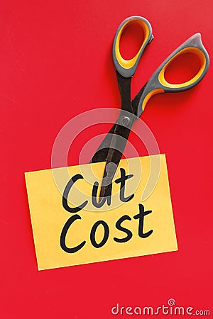 Cost Cutting Concept. Scissors Cutting Through Yellow Sticky Note Stock Photo