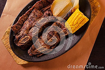 Costillitas Mexican Food served with fried onion and corn on the black plate Stock Photo