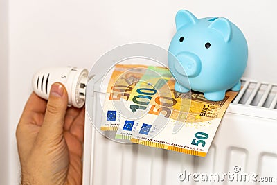 costs of heating apartments in winter in the European Union, energy and economic concept, hand unscrewing the radiator, piggy bank Stock Photo