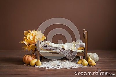 Cot for newborn children on a brown chocolate background with pears, pumpkins Stock Photo