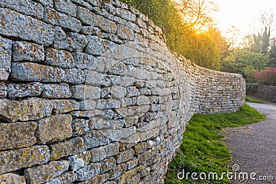 Cotswolds stone fence shown in leading perspective with sun flare Stock Photo