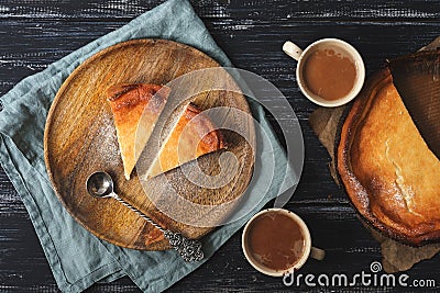 Cottage cheese cake is served on a wooden plate in a rustic style. Coffee, napkin, spoon, wooden background. Stock Photo