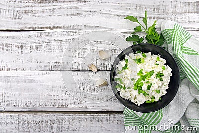 Cottage cheese with chives in black ceramic bowl on rustic woode Stock Photo