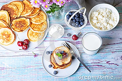 Cottage cheese pancakes syrniki. Homemade cheesecakes from cottage cheese with sour cream, berries and milk. Stock Photo