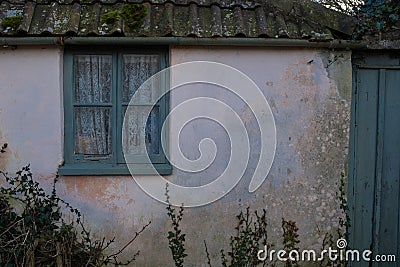 Cottage needs some love, window and gate of a rural cottage Stock Photo