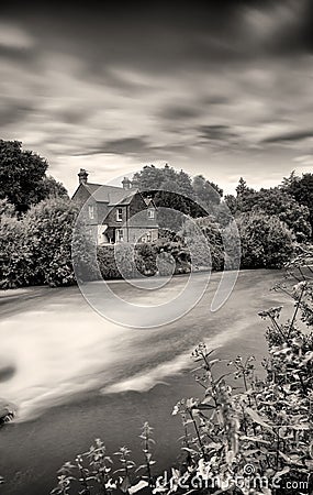 English cottage by a weir Long exposure. Stock Photo