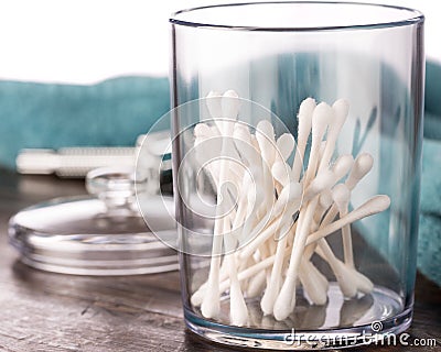 Cotton swabs in clear plastic jar in bathroom setting Stock Photo