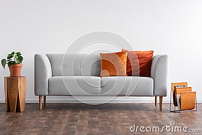 Couch with pillows between wooden table and newspaper organizer, real photo with copy space on the empty white Stock Photo