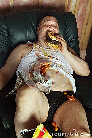 Couch potato eating and watching TV Stock Photo