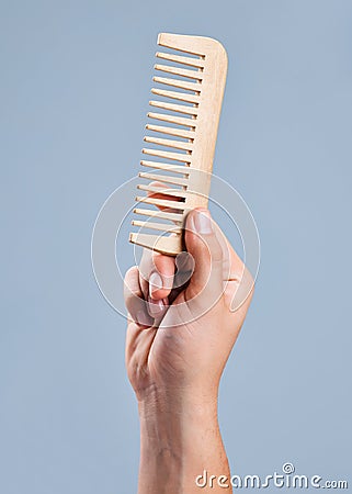 This could untangle the Gordian knot. an unrecognizable man holding a comb against a blue background. Stock Photo