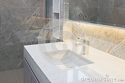 Counter top white marble with washbasin.Wall and floor beige,grey marble stone interior design of restroom or toilet background.Re Stock Photo
