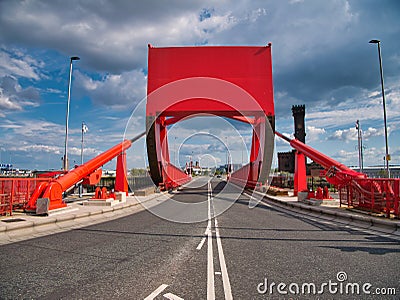 The counterweight and hydraulic rams of a red bascule bridge carrying road and pedestrian traffic across part of the docks complex Editorial Stock Photo