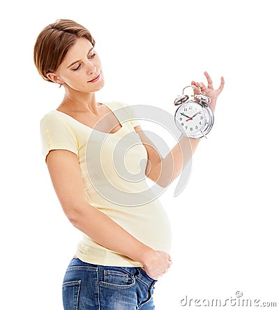 Counting down the time until the baby arrives. A pretty pregnant woman holding a clock while isolated on a white Stock Photo