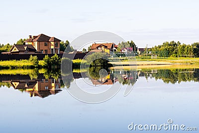 Country houses on the lake behind the trees, the reflection of houses in the water Stock Photo