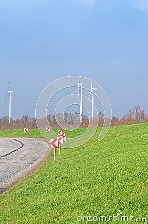 Country Road, green meadow and three wind turbines on the blue sky Stock Photo