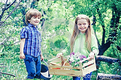 Countryside childhood. Happy kids work, plant and water in green spring garden. Eco garden workers. Cute boy and girl Stock Photo
