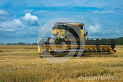 countryside harvest: yellow combine harvester collecting wheat under a clear blue sky Stock Photo