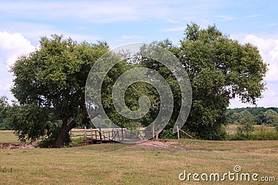 Countryside landscape with an old wooden bridge over the river Stock Photo