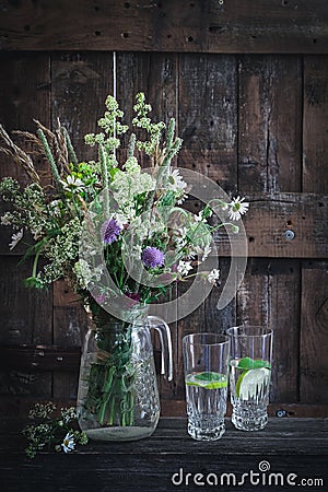 Countryside scene with wildflowers in a vase and glasses with water Stock Photo