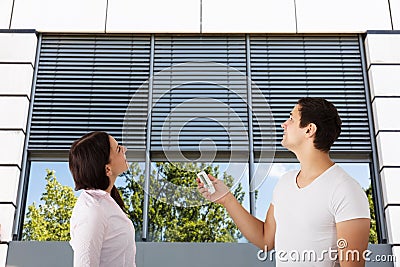 Couple Using Remote To Open Window Shutter Stock Photo