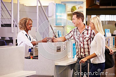 Couple At Airport Check In Desk Leaving On Vacation Stock Photo