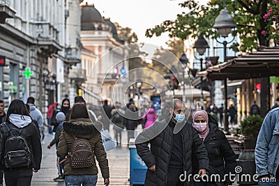 Couple, arabic middle eastern, with a woman with an islamic scarf veil walking in a Belgrade street wearing face mask protective Editorial Stock Photo