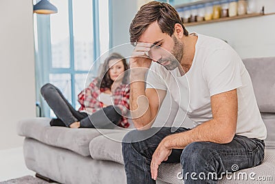 Couple argue. The wife shouted to her desperate husband, sitting on the couch in the living room at home. A man does not Stock Photo